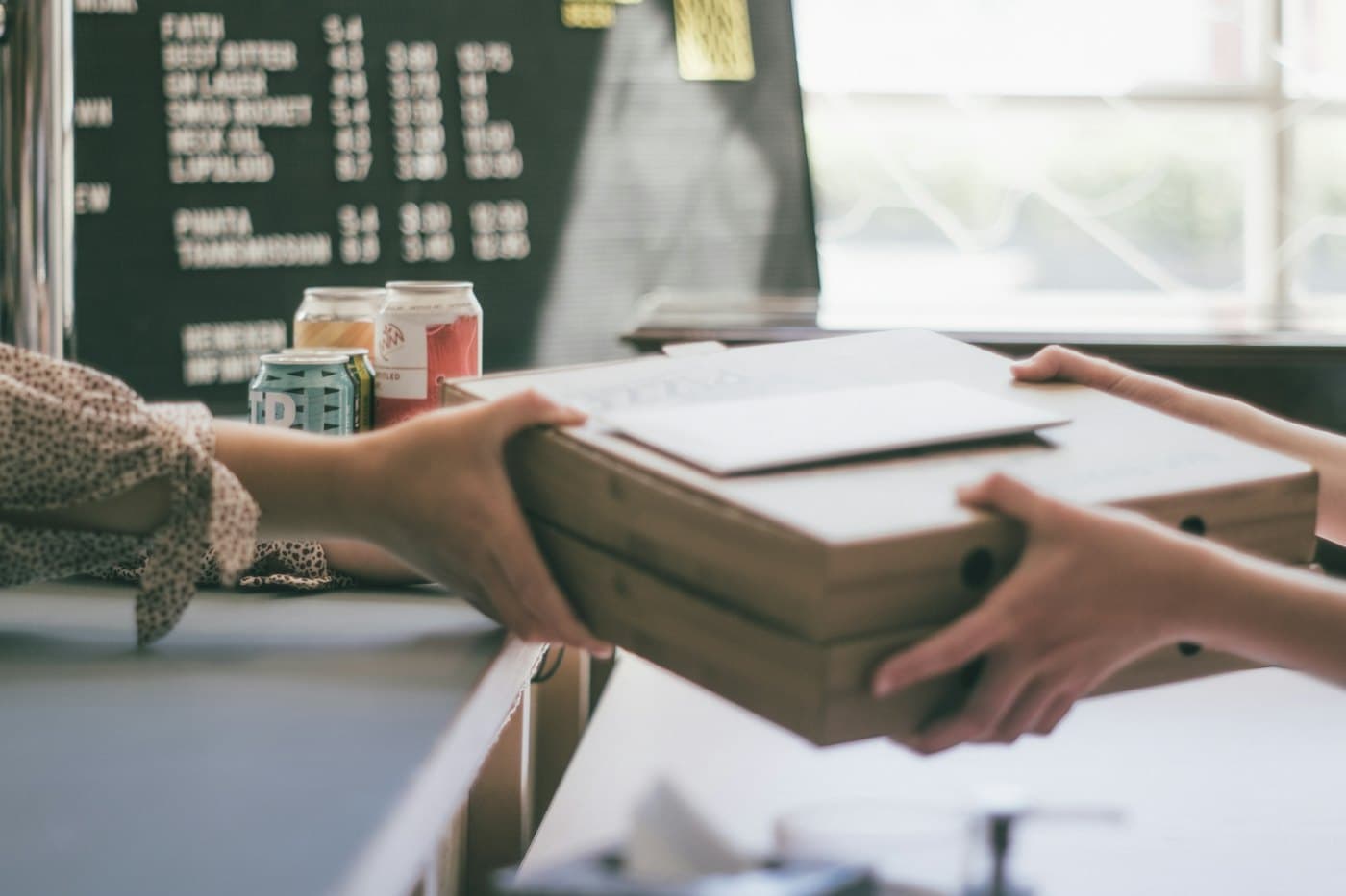 Des mains échangeant un colis emballé, comme une première commande expédiée