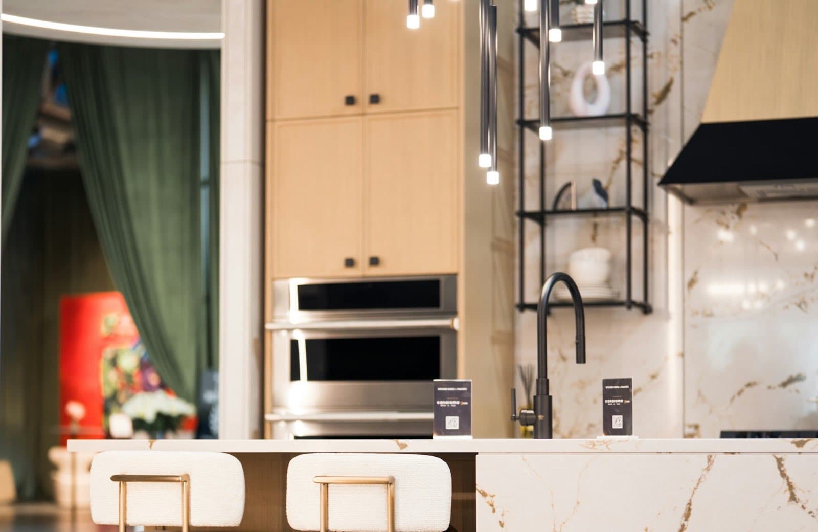 Une cuisine contemporaine avec un îlot en marbre, des tabourets et un grand luminaire