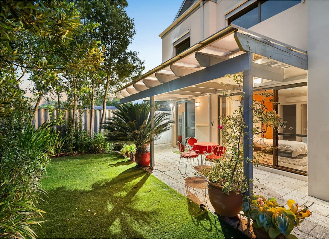 Une terrasse couverte avec sa table et ses chaises, ouverte sur un jardin