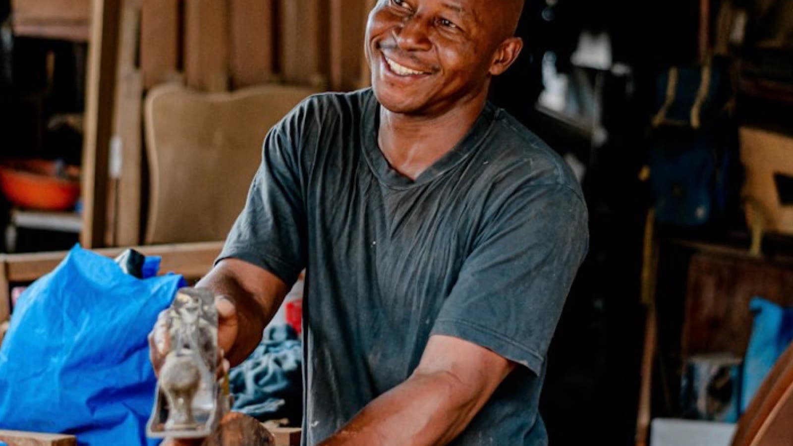 Un artisan sourit en travaillant une pièce de bois dans son atelier